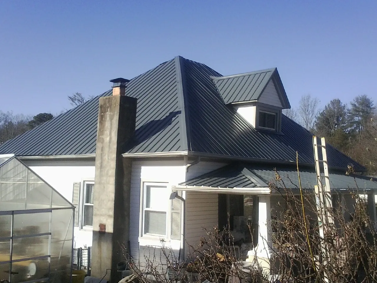 Dark blue standing seam metal roof on a white farmhouse with dormer — Slate & Tile Roof Repair by Roofing Brothers in Red Hook