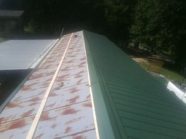 Old rusted panels beside newly installed green metal roofing — Wind Damage Roof Repair by Roofing Brothers in Red Hook