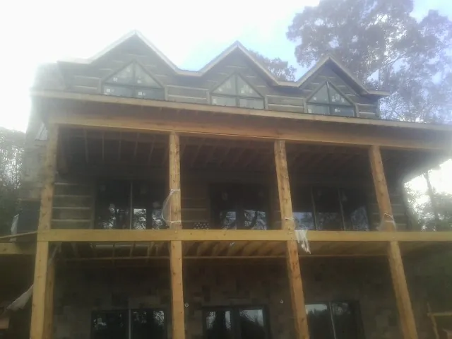 Dormers and porch framing on a large log home under construction — Roof Coating work by our crew in Red Hook