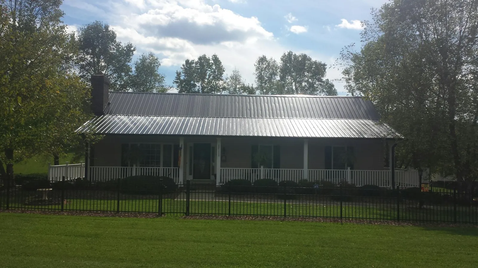 Gray metal roof on a brick ranch with a full width front porch — Gutter Guard Installation work by our crew in Red Hook