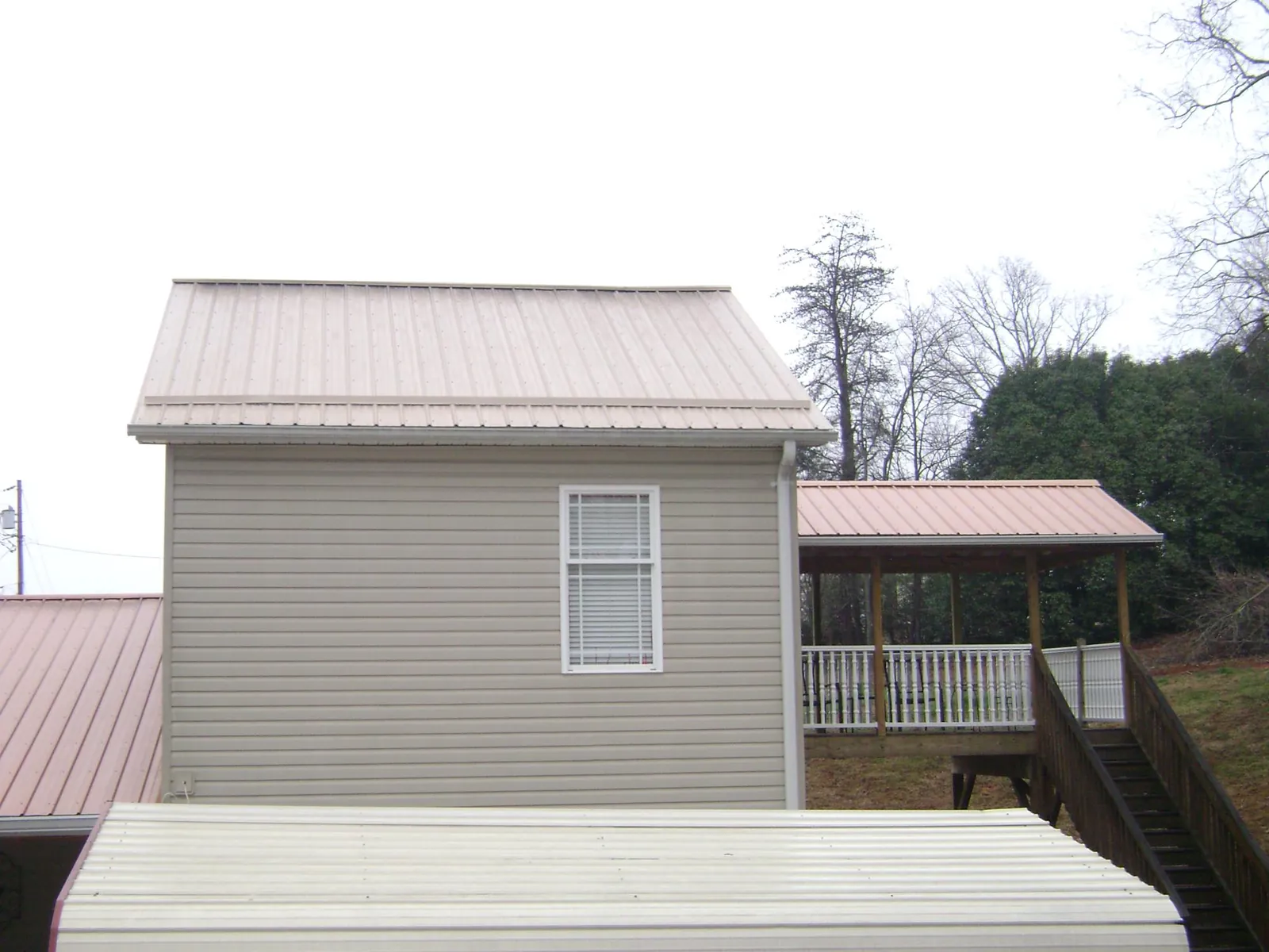 Tan metal roofs on a two story addition and attached porch, from a Roof Replacement job in Red Hook